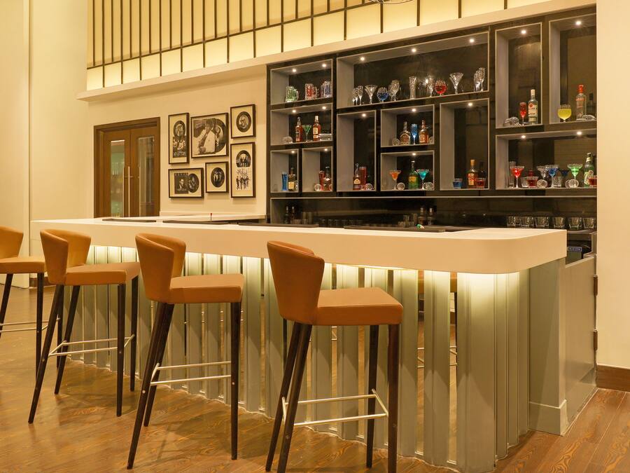 Un espace bar avec des tabourets, des étagères remplies de bouteilles et des tableaux encadrés au mur.