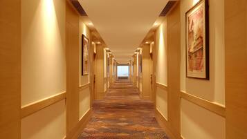 Un pasillo de hotel con alfombra estampada, paneles de madera y cuadros en las paredes.