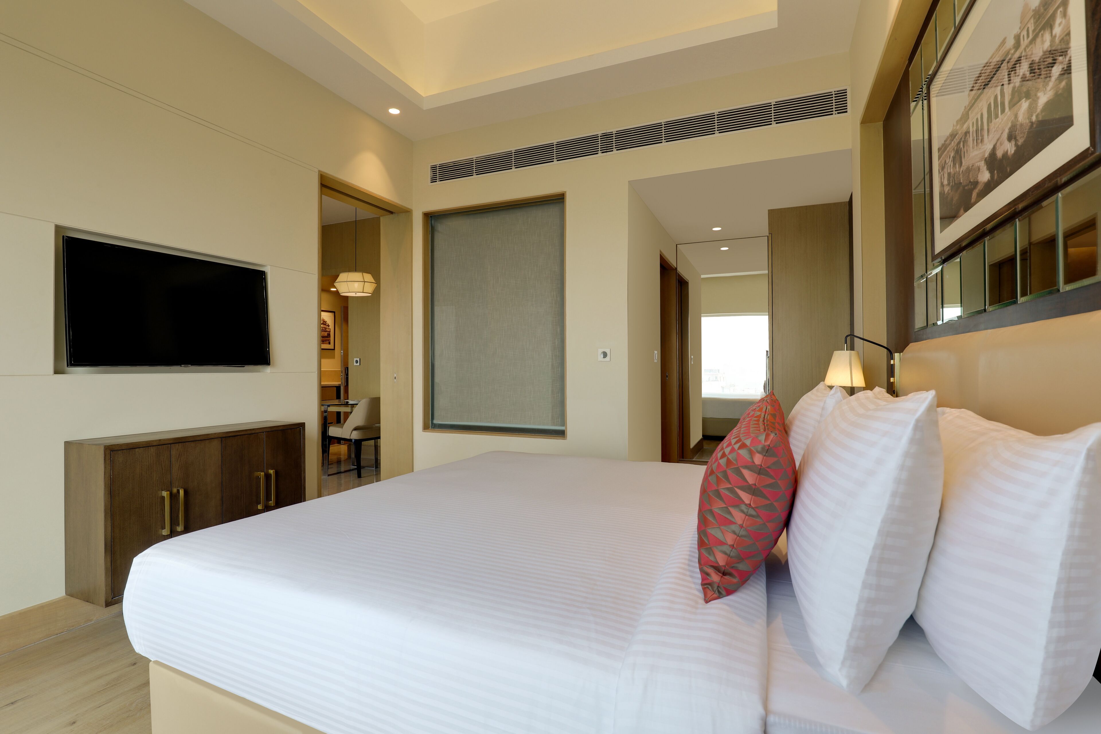 A hotel room with a large bed, a flat-screen TV, a wooden cabinet, and a framed picture on the wall.