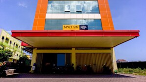 A multi-story building with a yellow and red facade, a covered entrance, and a sign indicating a spot for parking. - Pondok Bintang (Somba Opu)