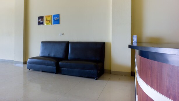 A reception area with a black leather sofa, a wooden reception desk, and three wall-mounted signs. - Pondok Bintang (Somba Opu)