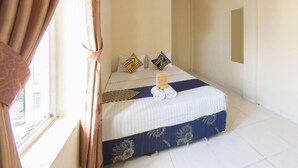 Una habitación de hotel con cama, cortinas, un cartel y una ventana.