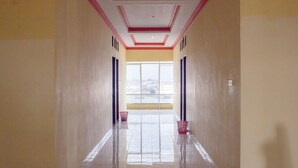 A corridor with a tiled floor, a window at the end, and a door on the left. - Pondok Bintang (Somba Opu)