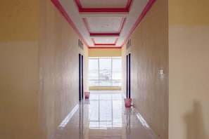 A corridor with a tiled floor, a window at the end, and a door on the left. - Pondok Bintang (Somba Opu)