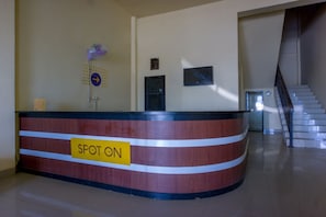 A reception desk with a 'SPOT ON' sign, a wall-mounted fan, and a staircase in the background. - Pondok Bintang (Somba Opu)