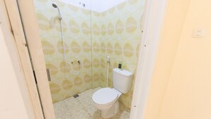 Un baño pequeño con inodoro, ducha y dispensador de papel higiénico.