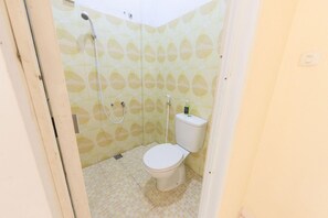 Ein kleines Badezimmer mit Toilette, Dusche und Toilettenpapierhalter.
