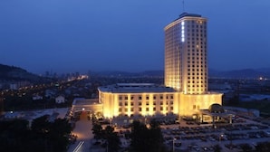 A high-rise hotel with a central courtyard and a parking area.
