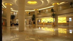 A spacious lobby with high ceilings, large columns, and a reception desk with a marble counter.