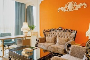 Una habitación con un sofá capitonado, una mesa de centro de vidrio y una mesa de comedor con sillas.