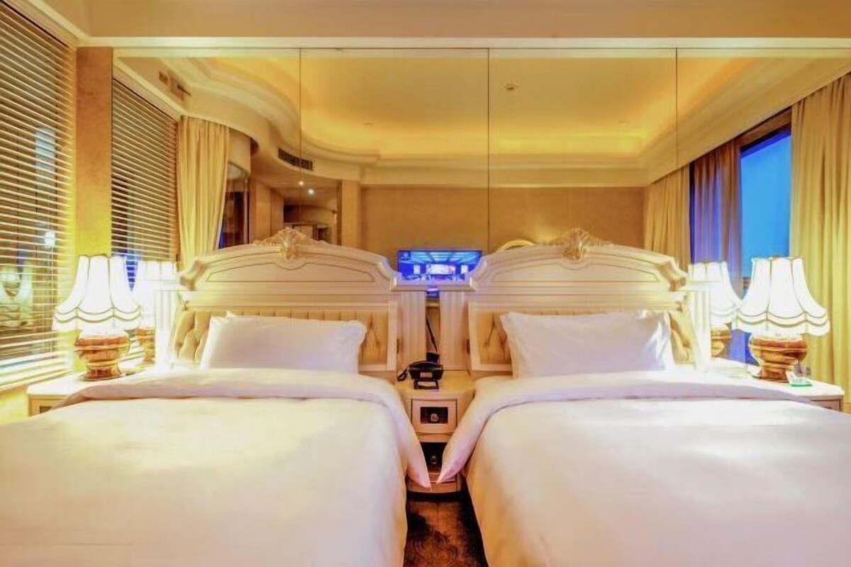 Habitación de hotel con dos camas, televisión y minibar.