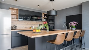 A modern kitchen with a central island, bar stools, and a variety of kitchen appliances.