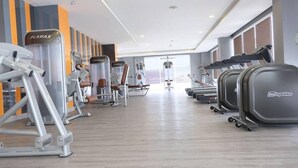 Una palestra con diverse attrezzature per l'allenamento, tra cui tapis roulant, cyclette e macchinari per pesi.