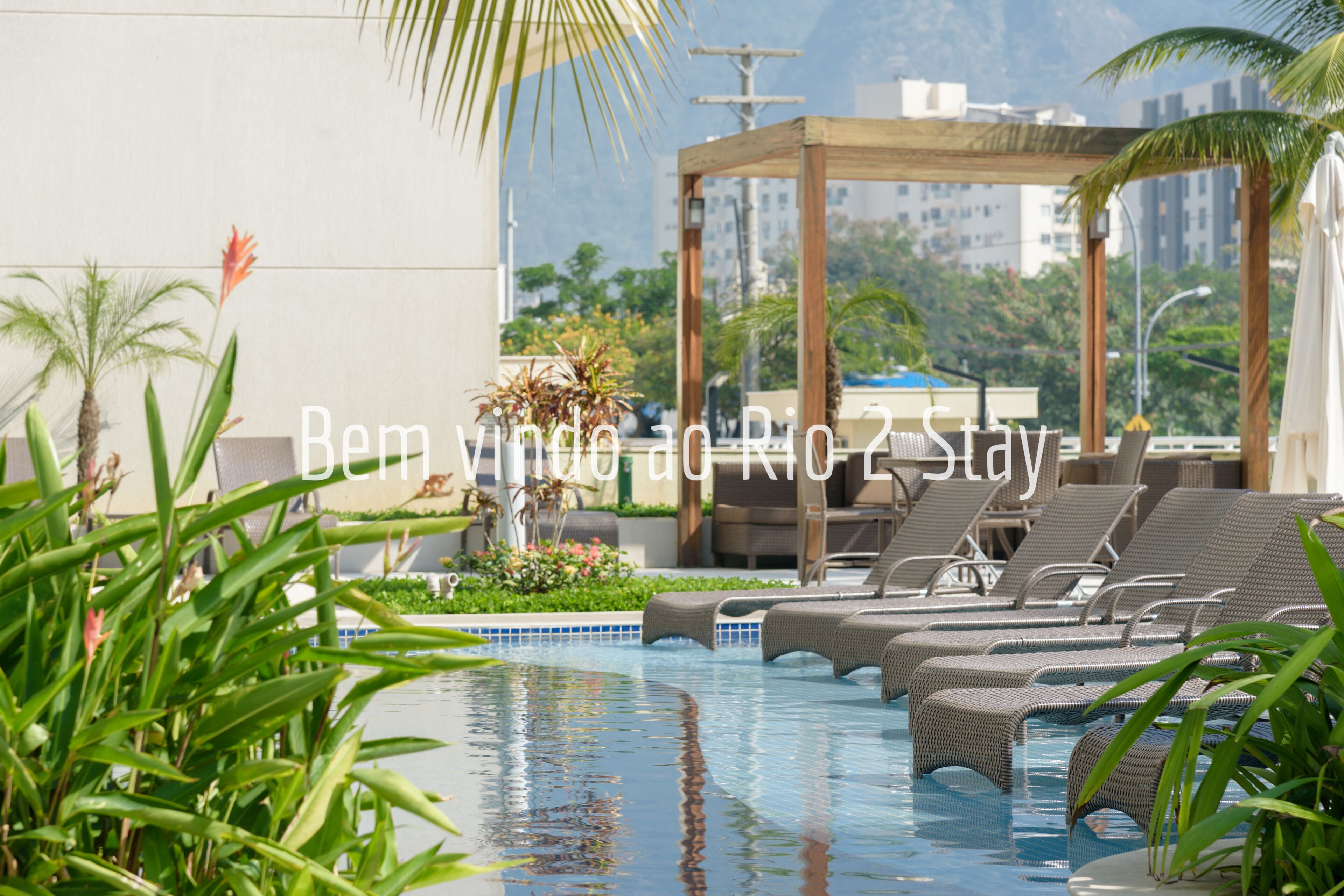 Un área de piscina en la azotea con sillones de descanso y una pérgola.