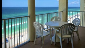 A balcony with a table and chairs overlooking a beach. - Affordable Beach Front Condo #2 (Panama City Beach)