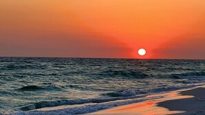 A sunset over the ocean with waves approaching the shore. - Affordable Beach Front Condo #2 (Panama City Beach)
