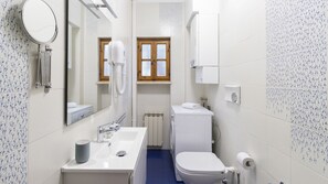 Et lille badeværelse med vask, toilet og spejl.
