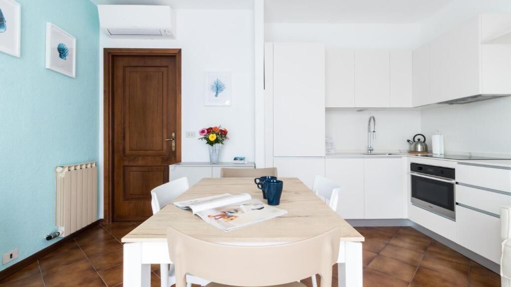Une cuisine moderne avec des meubles blancs, une table en bois et une tasse bleue.