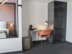 A modern hotel room with a desk, chair, and a large wardrobe. - B&B Hotel Böblingen (Boeblingen)