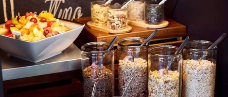 A breakfast buffet with a variety of fruits, cereals, and jams.