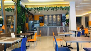Ein modernes Restaurant mit Barbereich, Holztischen und orangefarbenen Stühlen.