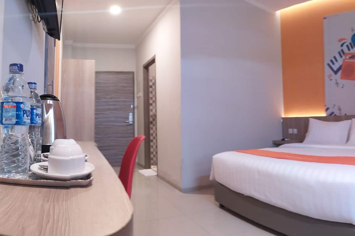 Ein Hotelzimmer mit Bett, Schreibtisch mit Stuhl, einer Kaffeemaschine und Wasserflaschen.