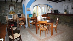 A dining area with wooden furniture, stone walls, and a stone fireplace. - Mary Anna Villa (Hersonissos)