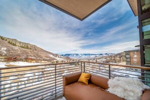 Un balcon donnant sur un paysage montagneux, avec un bâtiment visible au loin.