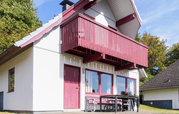 A two-story building with a balcony, large windows, and a door.