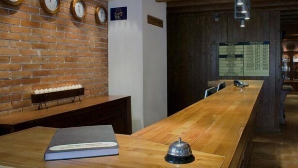 A reception area with a wooden reception desk, a book, and a bell. - Razlog Hotel (Razlog)