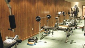 A gym with various exercise equipment, including a bench press, a squat rack, and a treadmill. - Razlog Hotel (Razlog)