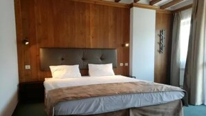 A bed with a wooden headboard, white bedding, and a brown accent. - Razlog Hotel (Razlog)