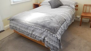 Une chambre à coucher avec un lit, une table de chevet, une lampe et une chaise.