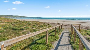 A wooden pathway leading to a beach with a clear view of the ocean and distant hills. - Black Pearl - Aldinga Beach - C21 SouthCoast Holidays (Aldinga Beach)