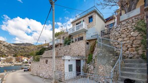 Un edificio costiero con muri in pietra, un balcone e una scala che conduce al piano superiore.