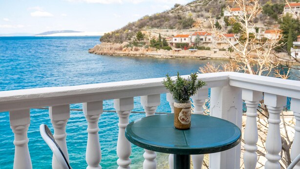 Un balcone con vista sul mare e un tavolino con una pianta.