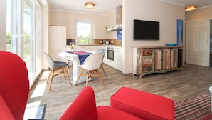 A modern kitchen with white cabinets, a dining table with chairs, and a TV mounted on the wall.