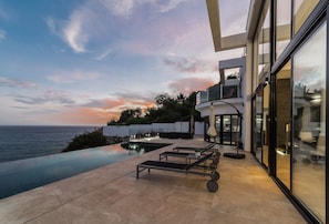 A modern house with a pool, outdoor seating, and a view of the ocean at sunset. - Beautifully located luxury private villa with heated pool and jacuzzi (Salobreña)