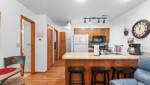 Una cocina moderna con armarios de madera, una isla central, taburetes de bar y una cafetera.
