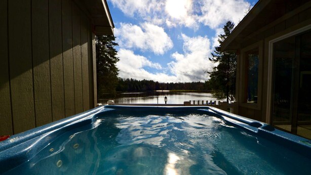 A hot tub with a view of a lake and trees, surrounded by wooden walls. - ⛷️⛱️⛰️Family Lake Home❤️3BR★HotTub★Fireplace★Games★Boat/Fish★Dogs+ (Pocono Lake)