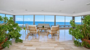 A spacious room with a large window overlooking the sea, furnished with wicker chairs and a central table. - Il Suono del Mare - Sea Front (Cervo)