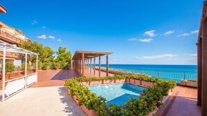 A rooftop pool with a view of the sea, surrounded by potted plants and a covered seating area. - Il Suono del Mare - Sea Front (Cervo)