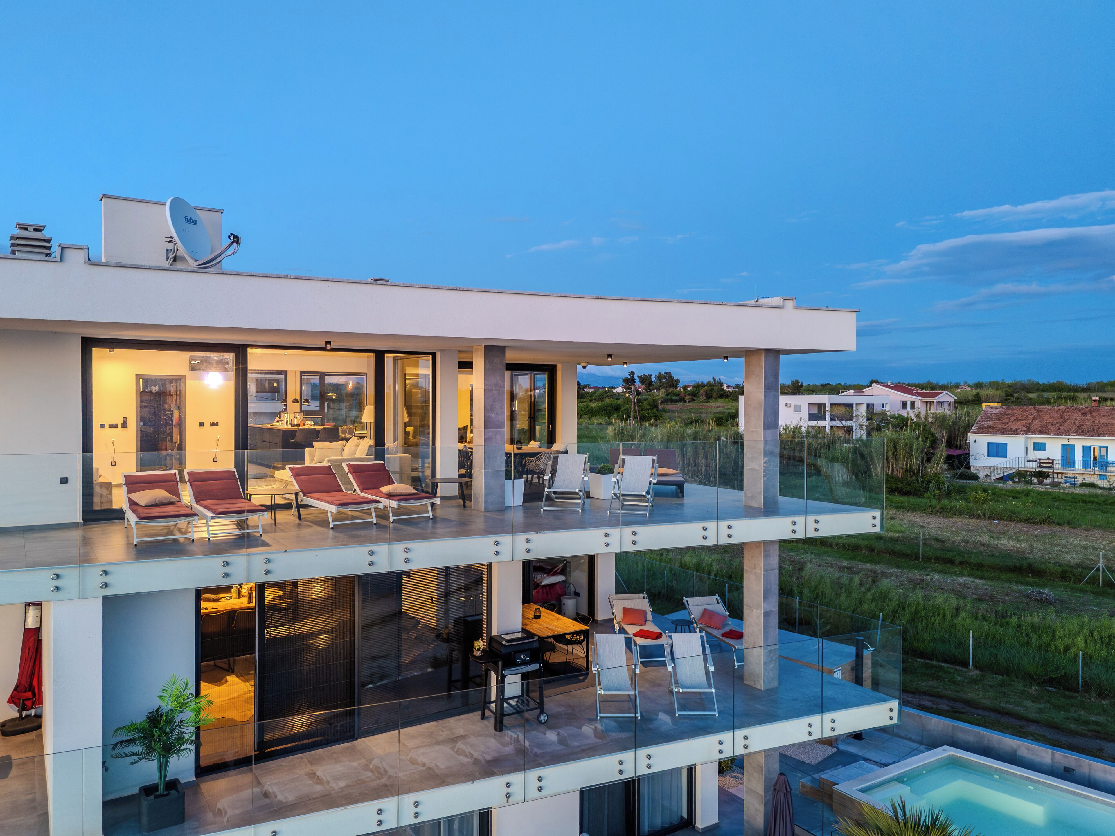 Ein modernes, zweistöckiges Haus mit Glasbalkon, Außenbereich und Pool.