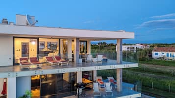 Ein modernes, zweistöckiges Haus mit Glasbalkon, Außenbereich und Pool.