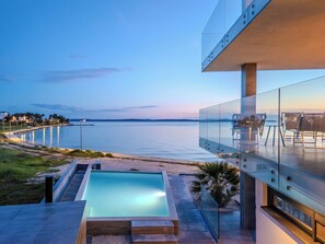 Ein modernes Gebäude mit einem Glasbalkon mit Blick auf das ruhige Meer.