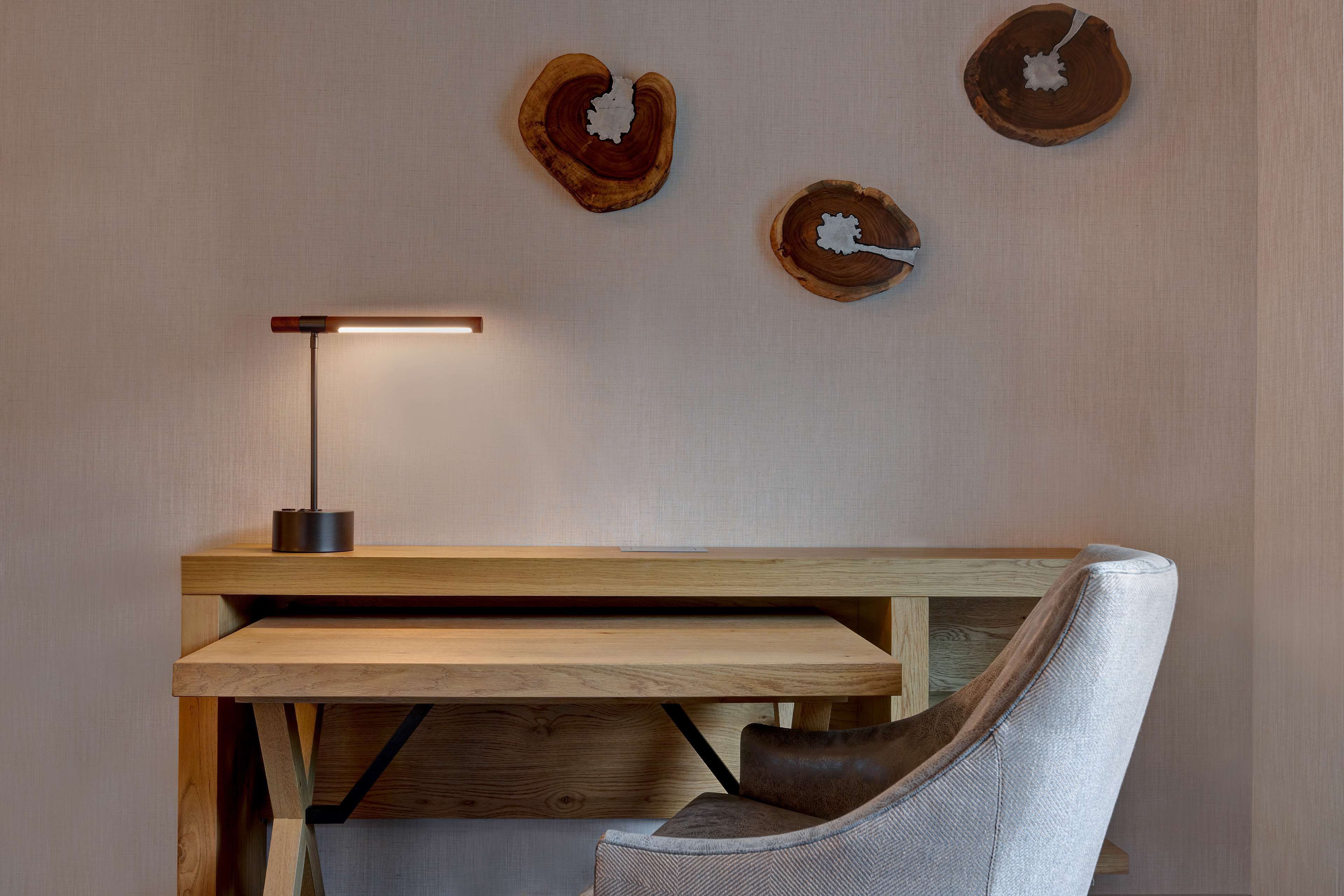 Een moderne kamer met een houten bureau, een stoel en houten kunstwerken aan de muur.