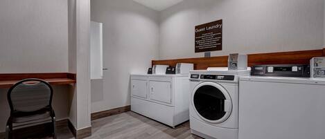 Una sala de lavandería con lavadora, secadora y una silla.