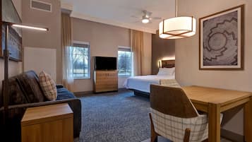 A hotel room with a bed, a desk, a chair, a television, and a ceiling fan.