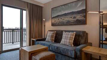 Une chambre d’hôtel avec une grande fenêtre, un canapé, une petite table et un tableau au mur.