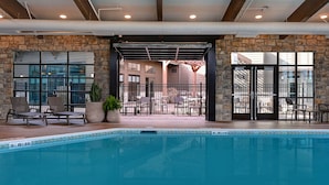 Une piscine intérieure dotée de chaises longues et d’un mur en pierre.